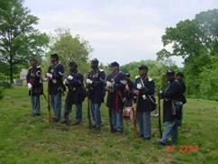 African American Civil War re-enactors line up to fire a rifle salute.