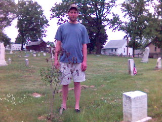 John Hand, neighbor of Midland Cemetery, stands behind one of the butterfly bushes that he donated and planted in the cemetery.